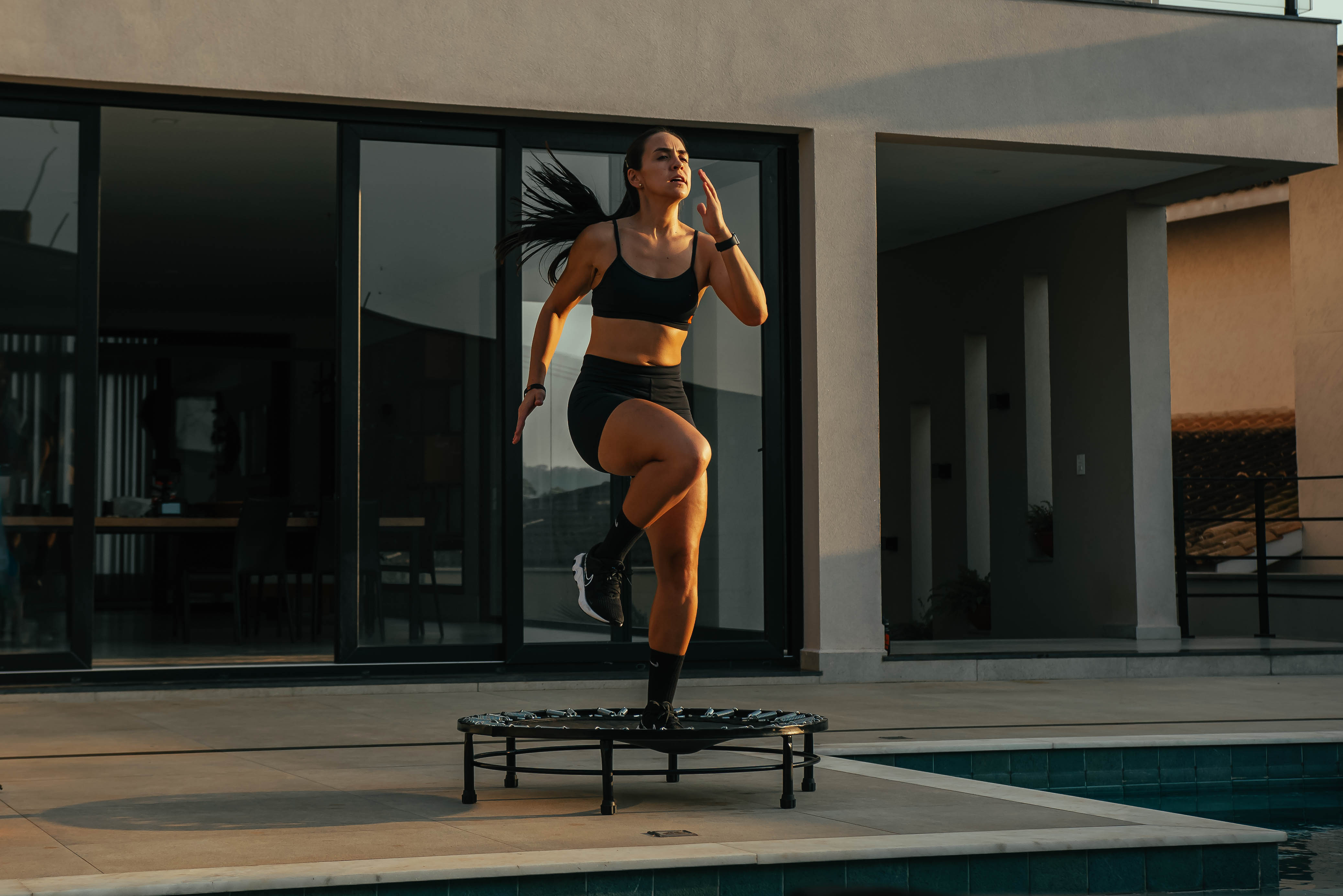 Mulher malhando em mini jump em casa ao ar livre